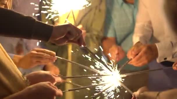 Hands of guests lighting sparklers at a party, close-up — Αρχείο Βίντεο