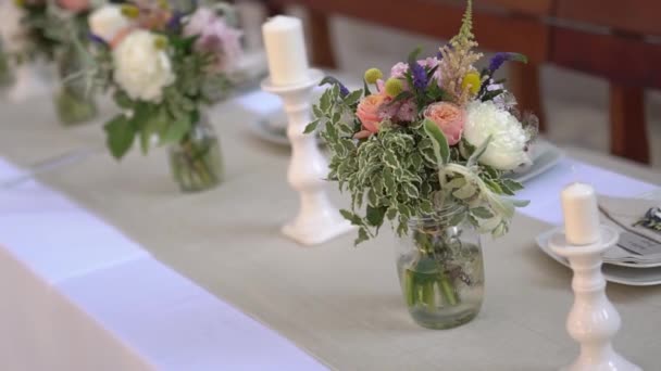 Felszolgálása és díszítése az asztal virágokkal és gyertyatartókkal az esküvői bankett — Stock videók