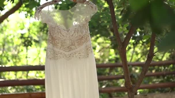 Мереживна весільна сукня, що висить на гілках дерев серед листя — стокове відео