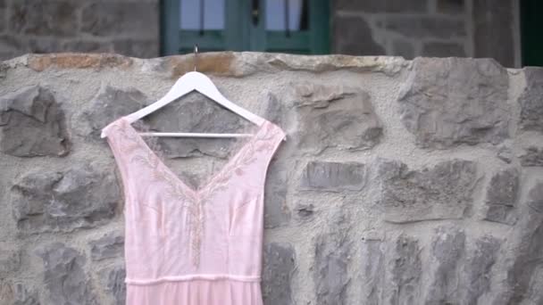 Perlenoberteil eines blassrosa Brautkleides, das an der Steinmauer hängt, Nahaufnahme — Stockvideo