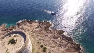 Denizden Karadağ 'daki Arza kalesine ve yanından geçen bir turizm teknesine bakın.