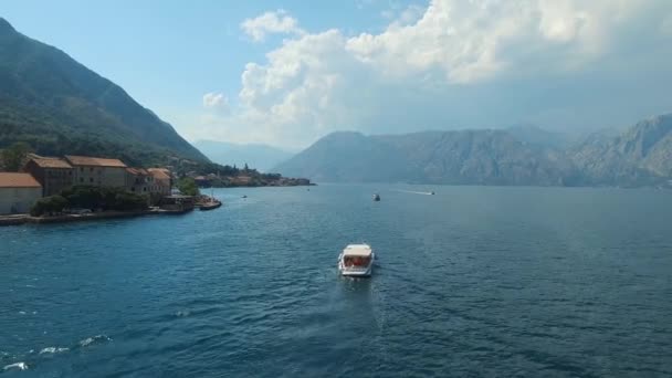 Sebuah perahu wisata layar di tengah-tengah Teluk Kotor, di depannya adalah kota kecil yang nyaman — Stok Video