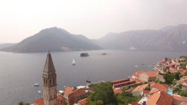 Eski Perast kasabası, dağlar, adalar ve yakınlarındaki bir yelkenli.