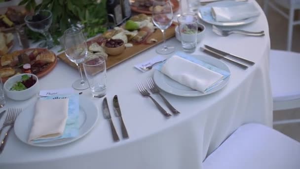 Een serveertafel versierd met een boeket bloemen en elegante witte stoelen op het bruiloft banket — Stockvideo