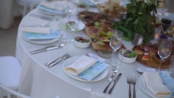 Una mesa de servicio decorada con un ramo de flores y elegantes sillas blancas en el banquete de bodas — Vídeos de Stock