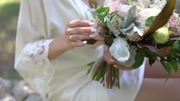 Una ragazza in un grazioso peignoir con un bouquet da sposa in mano — Video Stock