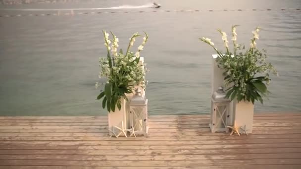 Lengkungan pernikahan di dermaga dengan latar belakang laut dan pegunungan - karangan bunga, bintang laut dan lentera dekoratif — Stok Video
