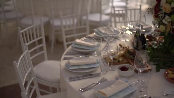 Düğün yemeğinde bir buket çiçekle süslenmiş servis masası ve zarif beyaz sandalyeler. — Stok video