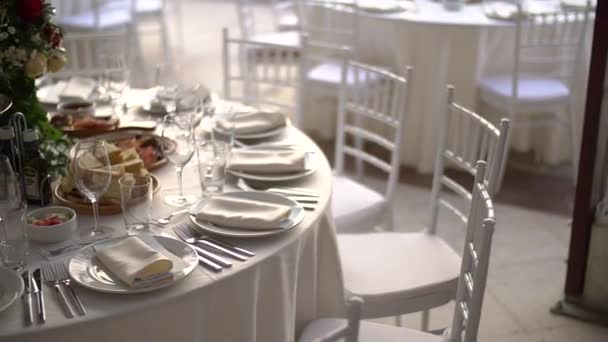 A serving table decorated with a bouquet of flowers and elegant white chairs at the wedding banquet — Stock Video