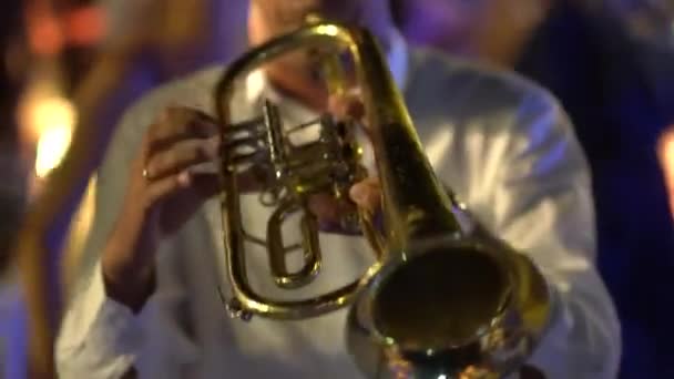 Der Musiker spielt auf der Party Trompete, die Leute tanzen hinter ihm — Stockvideo