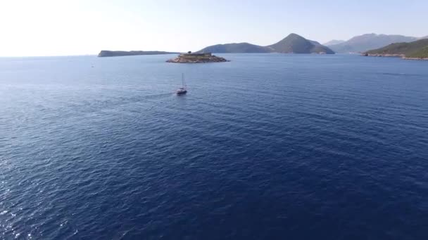 Θέα από τη θάλασσα προς το νησί της Μάμουλας στο Μαυροβούνιο και γιοτ κοντά σε αυτό — Αρχείο Βίντεο