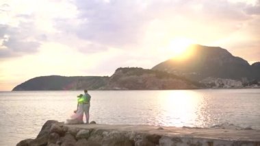 Gelin ve damat gün batımında iskelede sarılıyorlar.
