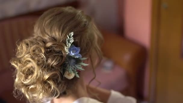 Belle coiffure avec des fleurs d'une mariée blonde se regardant dans le miroir — Video
