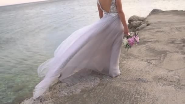 Наречена з весільним букетом прогулює пірсом, її спідниця мерехтить на вітрі — стокове відео