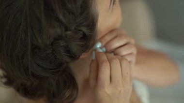 Gelin, düğün hazırlıkları sırasında kulağına küpe takar.