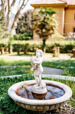Bahçesinde balık tutan bir çocuk figürü şeklinde küçük bir bahçe çeşmesi..