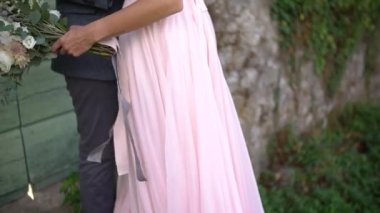 Damat, geline sırtı açık güzel bir elbiseyle sarılır. Gelin elinde bir buket tutar.