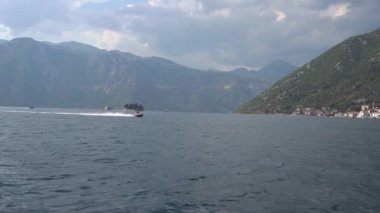 Sürat tekneleri Kotor Körfezi 'nin ortasında yelken açarlar. Arkasında küçük şirin adalar vardır.