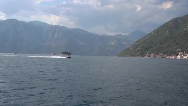 Motorboten varen midden in de baai van Kotor, daarachter liggen gezellige eilandjes — Stockvideo