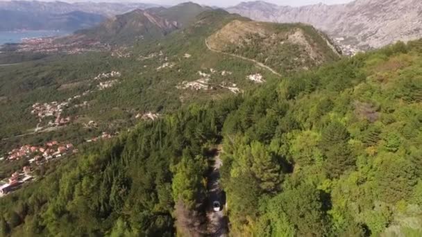 Bílý kabriolet jede po silnici na hoře Lovcen na pozadí malebného výhledu na záliv Kotor — Stock video