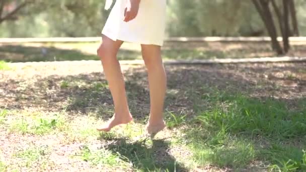 裸足の女の子で短いドレス草の上を歩くクローズアップ — ストック動画