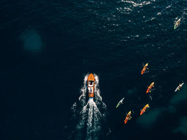 Lujosa lancha de madera se precipita a través de las olas del mar Adriático. Turistas navegan en kayaks con remos. — Foto de Stock