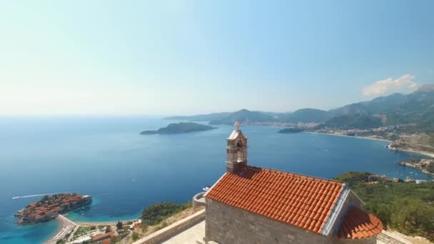 Prachtige oude Sveti Savva kerk met uitzicht op de kustlijn en het eiland Sveti Stefan — Stockvideo