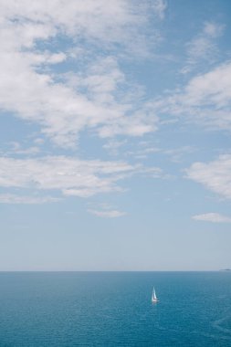 Seyahat konsepti arka planında - bulutlu mavi gökyüzü ile denizde küçük bir yelkenli.