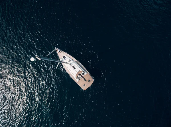 Vista aérea superior de um iate à vela com um mastro alto flutuando na água. — Fotografia de Stock