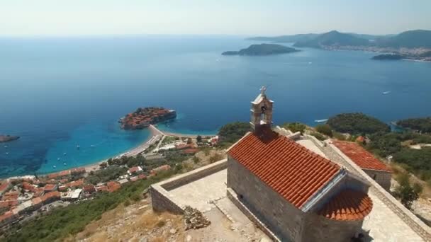 Belle ancienne église Sveti Savva surplombant le littoral et l'île de Sveti Stefan — Video