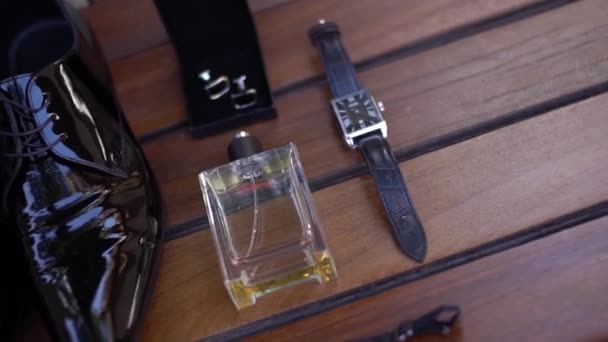 Lacquered mens shoes, wrist watch, perfume and cufflinks on wooden backgroun. close up — Stock Video