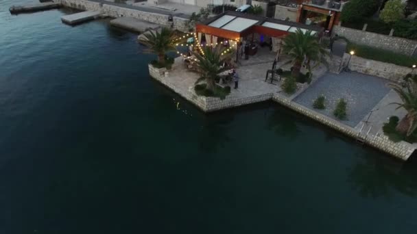 Útulná restaurace u moře s lesklými girlandami a svatební hostinou na molu v zátoce Kotor — Stock video