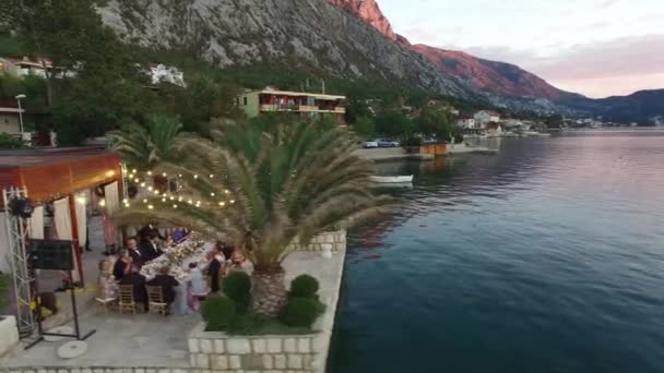 Útulná restaurace u moře s lesklými girlandami a svatební hostinou na molu v zátoce Kotor — Stock video