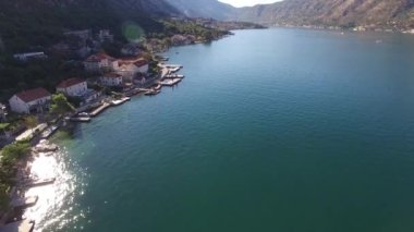 Kotor Körfezi 'nin küçük kasabasının manzarası güzel dağların eteğinde, parlak güneş suyun üzerinde parlıyor.