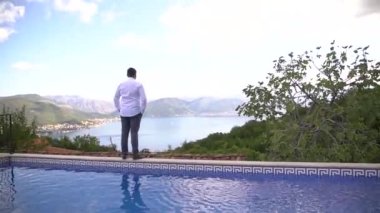 Beyaz gömlekli bir adam uzaklığa, arka manzaraya bakar.