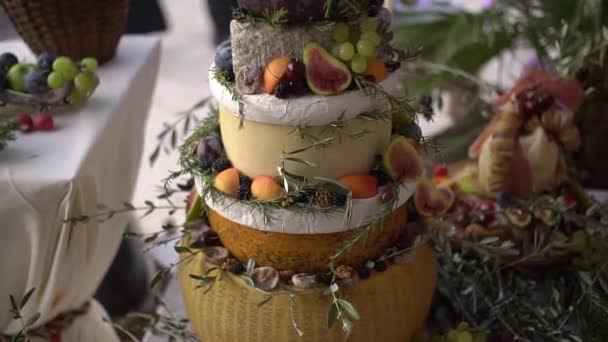 Сырные головка торт закуски, фрукты, орехи и зелень, цветочные украшения и различные закуски на свадьбе шведский стол — стоковое видео