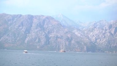 Turist teknesi ve yelkenli teknesi Kotor Körfezi 'ndeki pitoresk dağların arka planına karşı