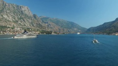 Yat, Kotor Körfezi boyunca ilerliyor. Arkasında güzel dağlar ve rahat küçük bir kasaba var.