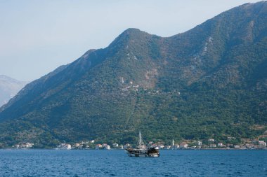 Güneşli bir günde Perast şehrinin kıyısında yelken açan bir yat..