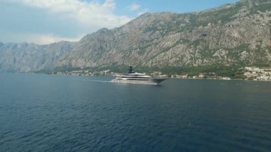 Yat, Kotor Körfezi boyunca ilerliyor. Arkasında güzel dağlar ve rahat küçük bir kasaba var.