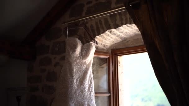 Hermoso vestido de novia con cuentas colgando cerca de la ventana abierta — Vídeos de Stock