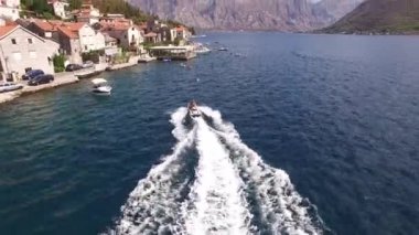 Bir motorlu tekne Kotor Körfezi 'ndeki Perast sahiline doğru yelken açar. 