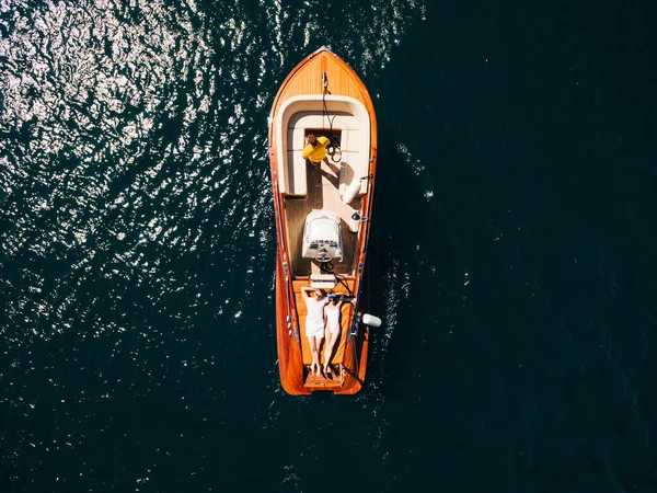 Um homem e uma mulher a bordo de um barco a motor em um dia ensolarado correm pela água. — Fotografia de Stock