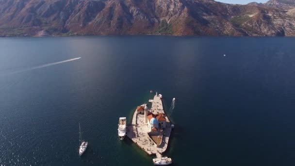 Vista superior da Nossa Senhora das Rochas ilha, iates e barco turístico perto dele na Baía de Kotor — Vídeo de Stock