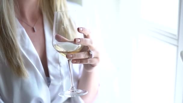 Жінка сидить біля вікна в халаті з келихом шампанського — стокове відео