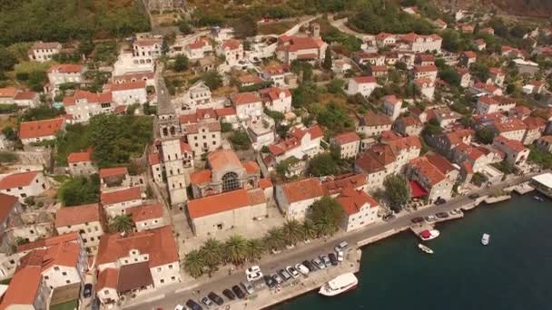 Utsikt över byggnader i den gamla staden Perast, berg, päron och båtar nära den — Stockvideo