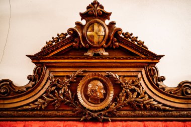 Kol şeklinde oyulmuş ahşap bir şablon, bir haç ve bir erkeğin yüzü.