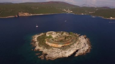 Antik Mamula kalesinin manzarası, ona yakın bir yat ve körfez kıyısı. 