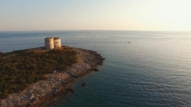 Karadağ 'ın Lustica yarımadasındaki antik kale Arza' nın günbatımında, yakınlarda bir tekne denize açılıyor 