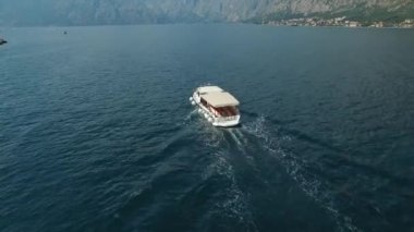Kotor Körfezi 'nin ortasından bir turist teknesi geçiyor.